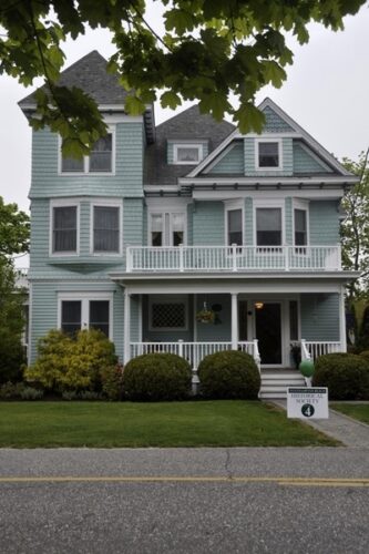 three storey light green historic house with white trim