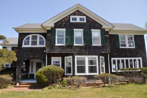 family home with dark wood shake siding and green shutters