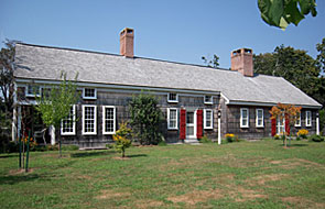 cape style house with wood shakes and green grass lawn