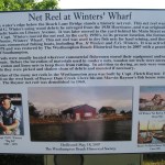 Historic sign describing the net reel at Winter's Wharf, including a photograph of a fisherman, an image of the wharf, and details about its history and significance.